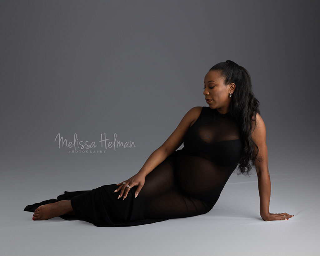 Maternity session with woman laying on her side in a black dress