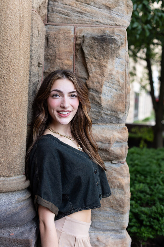 girl leaning on stone wall and looking at camera