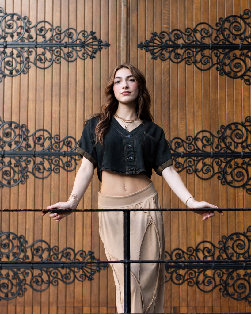 Girl holding railing in front of wood door with black latis