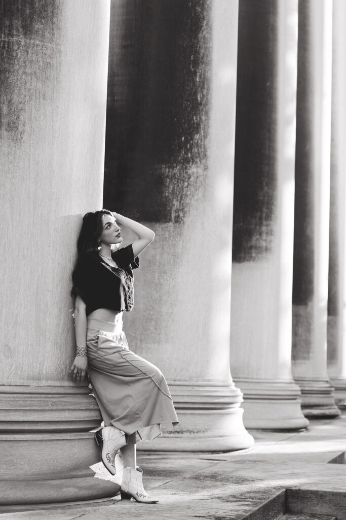 girl leaning on stone pillar with hand in hair