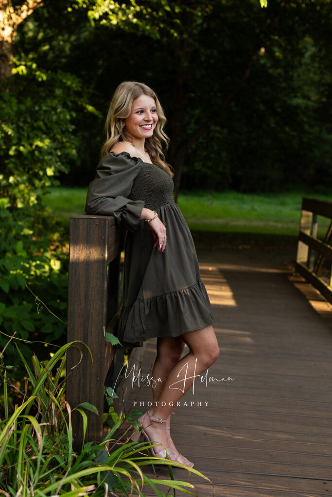 Senior girl sitting on bridge at University of Pittsburgh Greensburg during senior photo session.