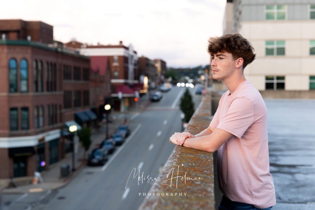 Senior guy smiling in front of unique city architecture during his Pittsburgh senior pictures