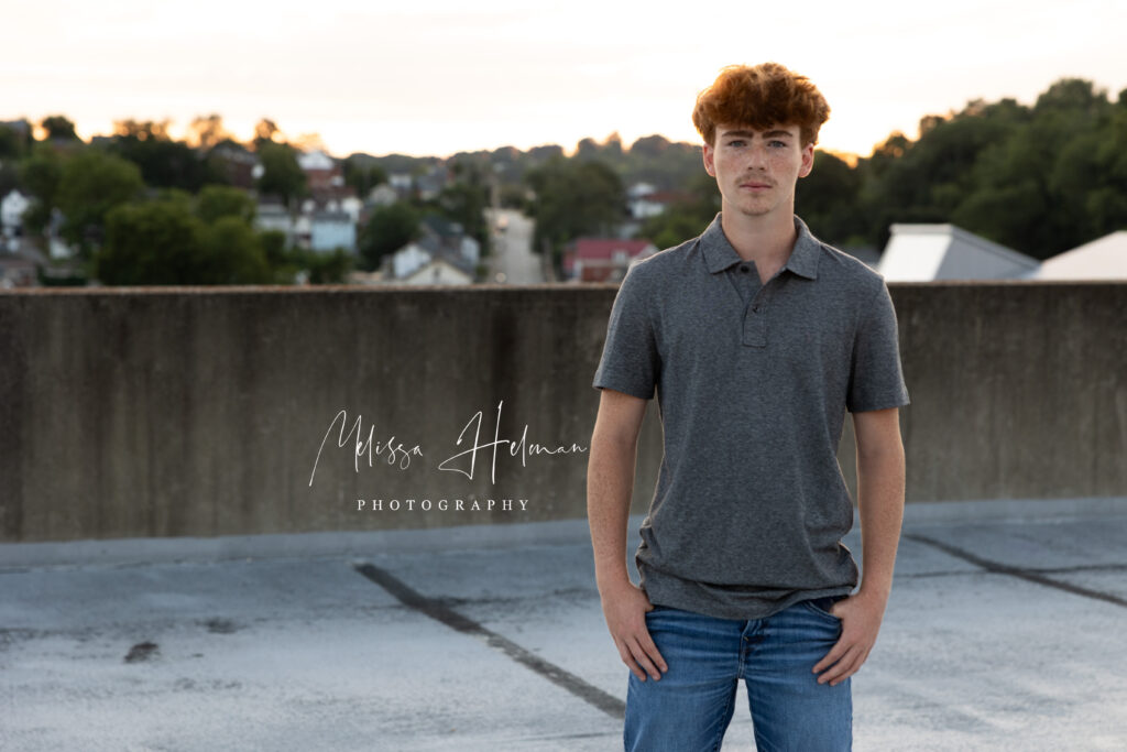 Senior guy smiling in front of unique city architecture during his Pittsburgh senior pictures