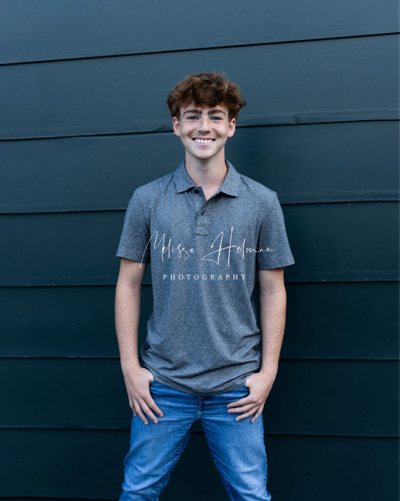 Senior guy smiling in front of unique city architecture during his Pittsburgh senior pictures