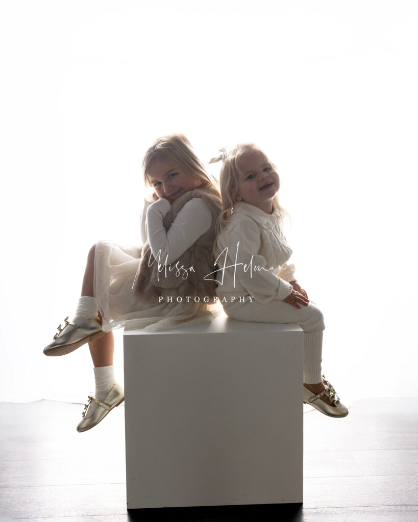 siblings sitting in soft white light for holiday session in Murrysville portrait studio