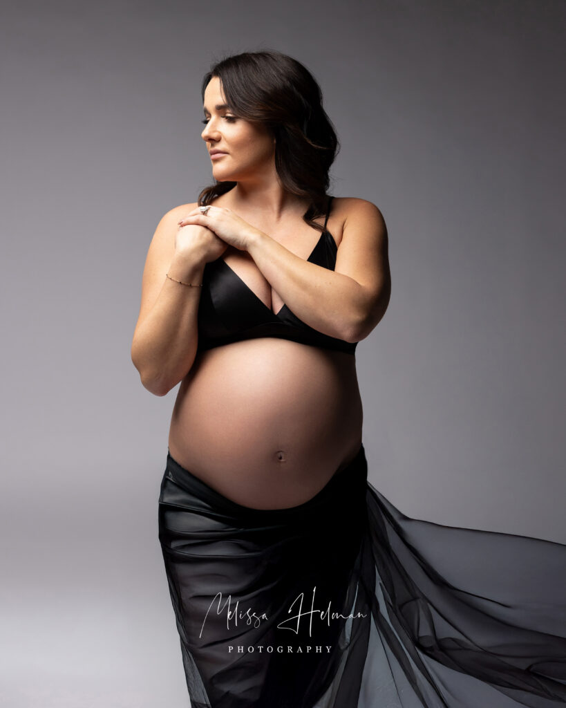black fabric flowing skirt for maternity session with hands on chest